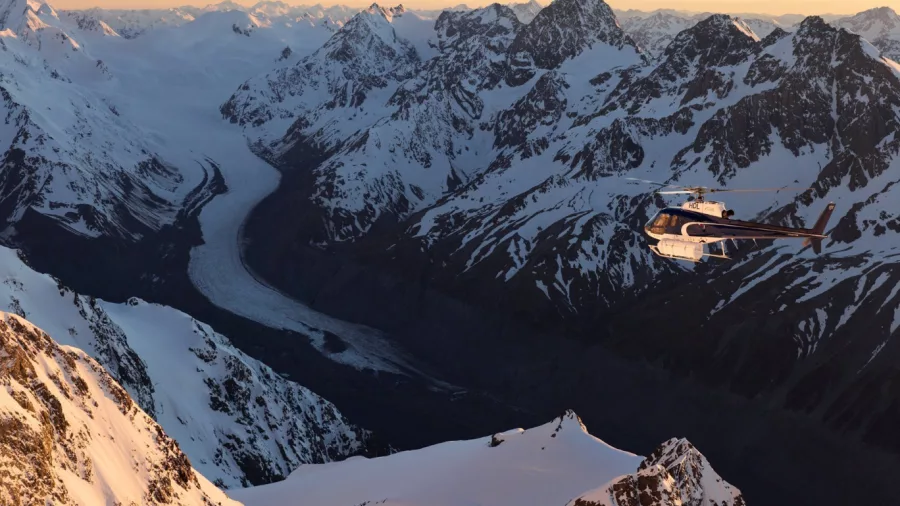 Helicopter flying over Tasman Glacier at sunrise with mountain peaks in view