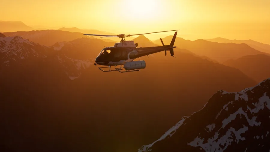 Helicopter flying at sunset above shadowed mountain peaks near Lake Tekapo