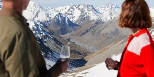 Two guests enjoying whisky with panoramic alpine views in the Southern Alps