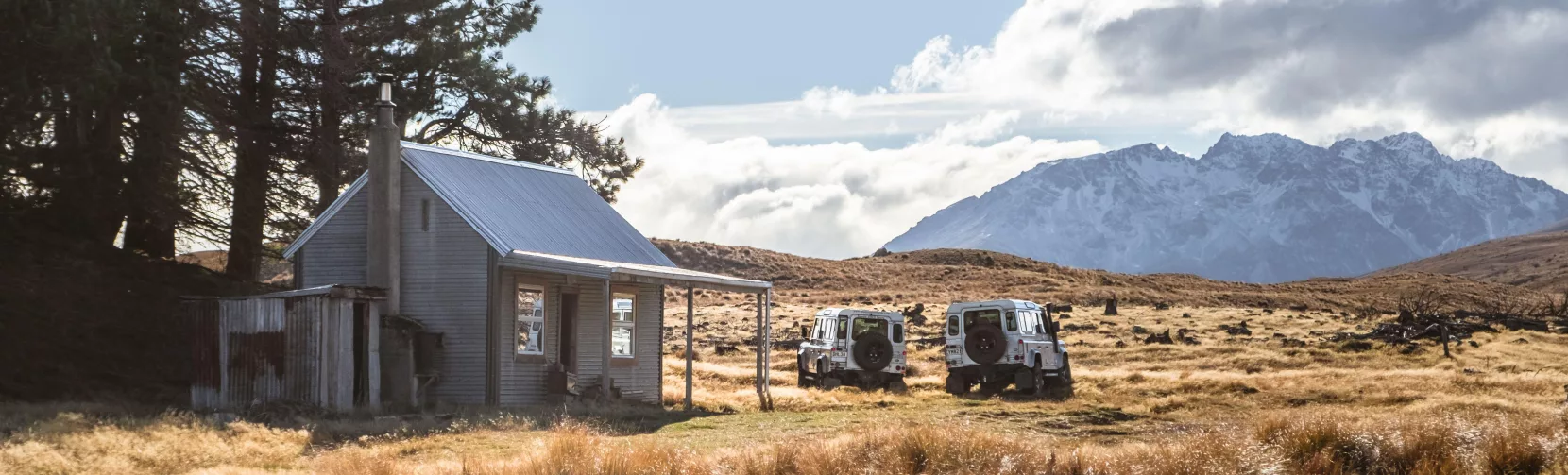 Remote hut at Braemar Station with 4WD vehicles parked under alpine skies