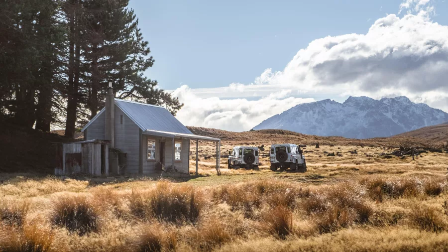 Remote hut at Braemar Station with 4WD vehicles parked under alpine skies