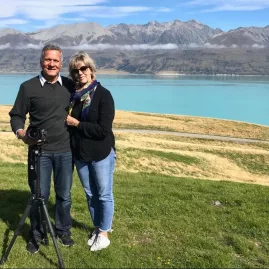 Couple smiling with tripod overlooking Lake Pukaki and Southern Alps during private tour