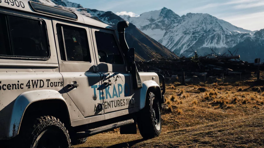 Tekapo Adventures 4WD parked with dramatic snow-covered peaks in the background