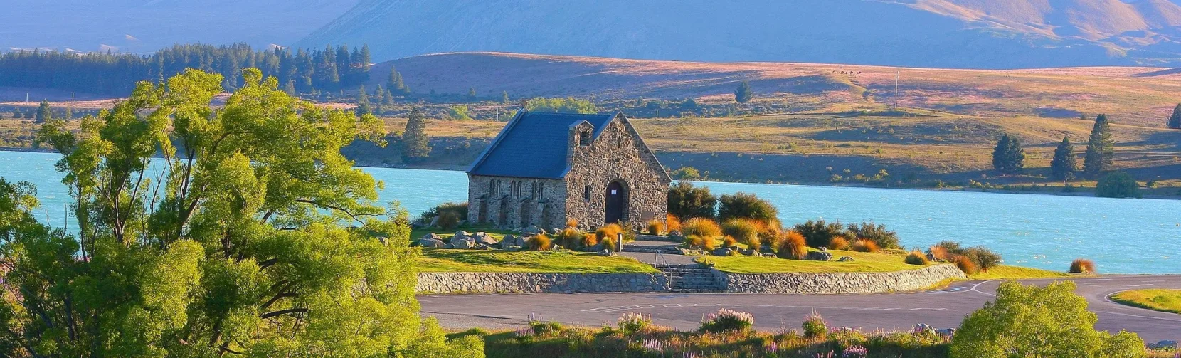 Church of the Good Shepherd overlooking Lake Tekapo, surrounded by purple lupins and mountain scenery