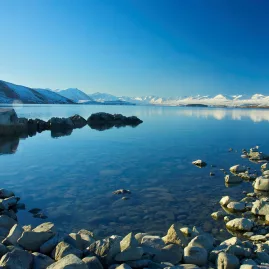 Snow-covered mountains reflecting on the calm waters of Lake Tekapo