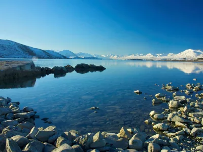 Snow-covered mountains reflecting on the calm waters of Lake Tekapo