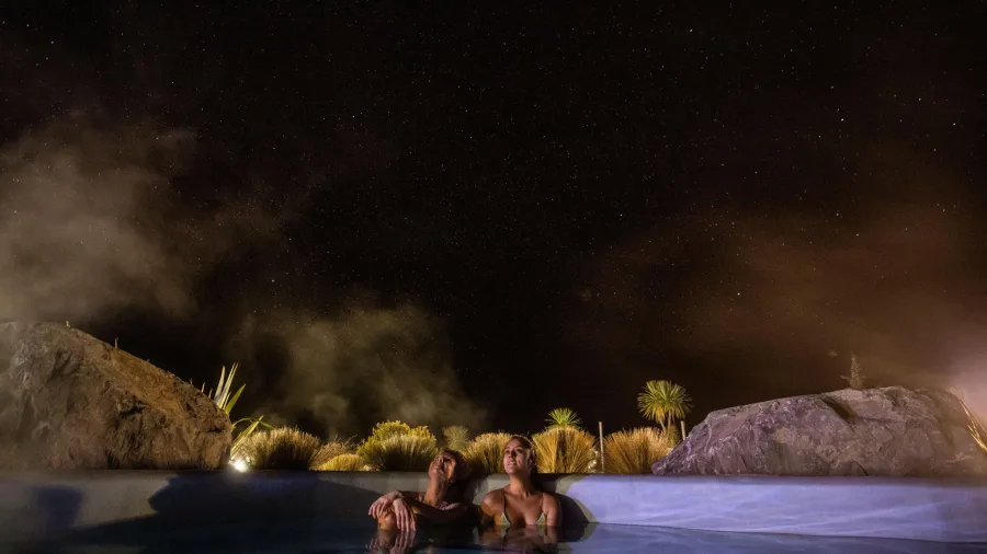 Couple relaxing at Tekapo Springs hot pools under a starry night sky