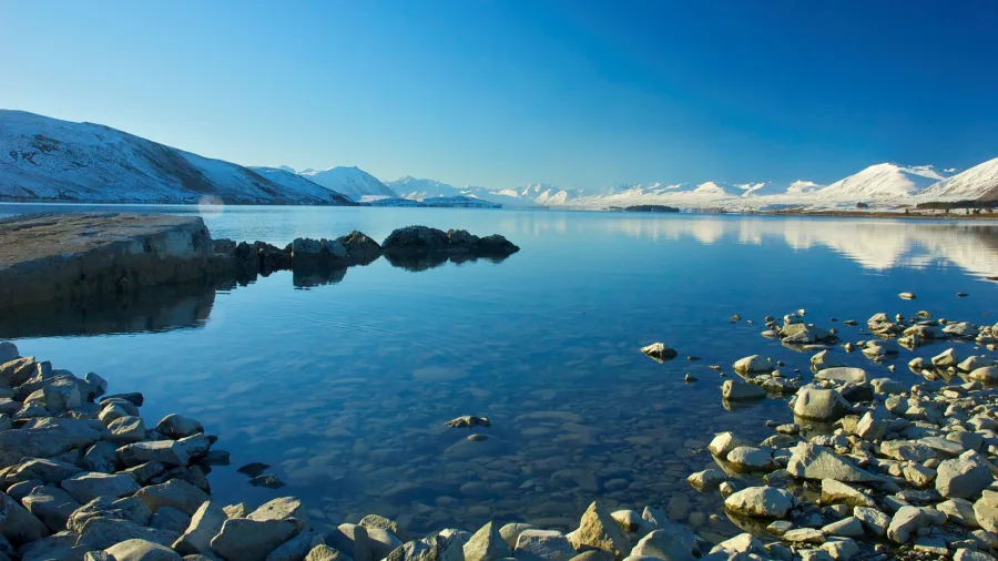 Snow-covered mountains reflecting on the calm waters of Lake Tekapo