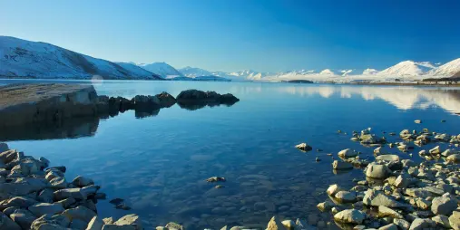 Snow-covered mountains reflecting on the calm waters of Lake Tekapo