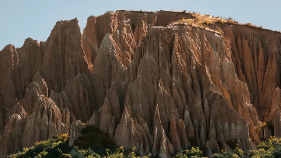Towering clay pinnacles at the Clay Cliffs near Omarama, bathed in sunlight.