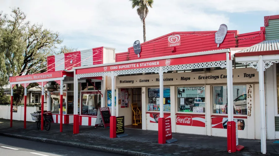Red and white Coro Superette and stationer shop on the historic main street of Coromandel town, New Zealand