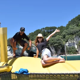 Guests smiling and posing on the front of the yellow sailing catamaran near Cathedral Cove