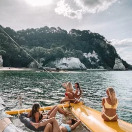 Group of women relaxing on a yellow sailing catamaran near Cathedral Cove