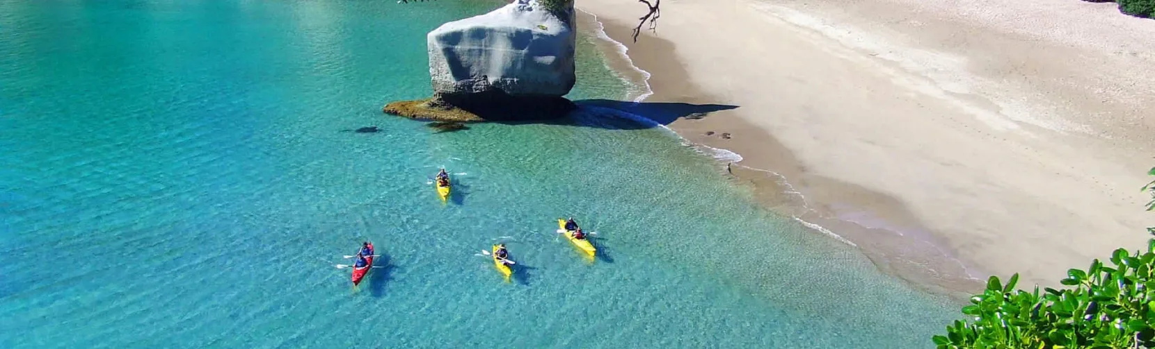 Aerial view of kayakers gliding over clear turquoise waters near Cathedral Cove