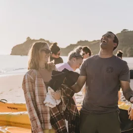 Kayak tour group laughing and preparing on the beach before launching at sunrise