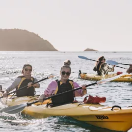 Happy kayakers paddling near Cathedral Cove on a calm sea