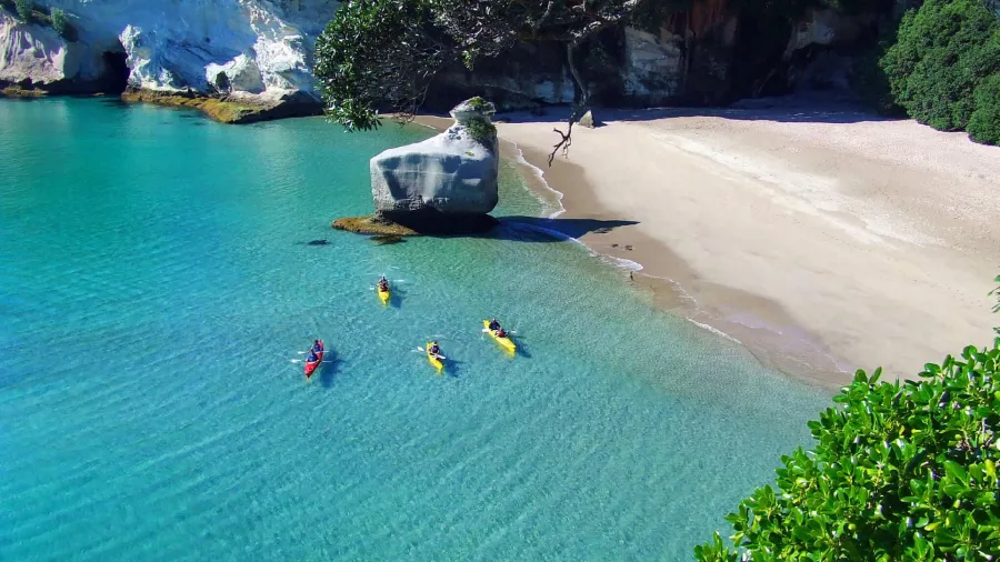 Aerial view of kayakers gliding over clear turquoise waters near Cathedral Cove