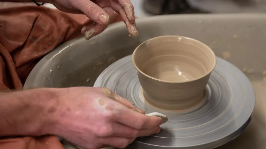 Close-up of hands shaping and finishing a pottery bowl on the wheel at Driving Creek