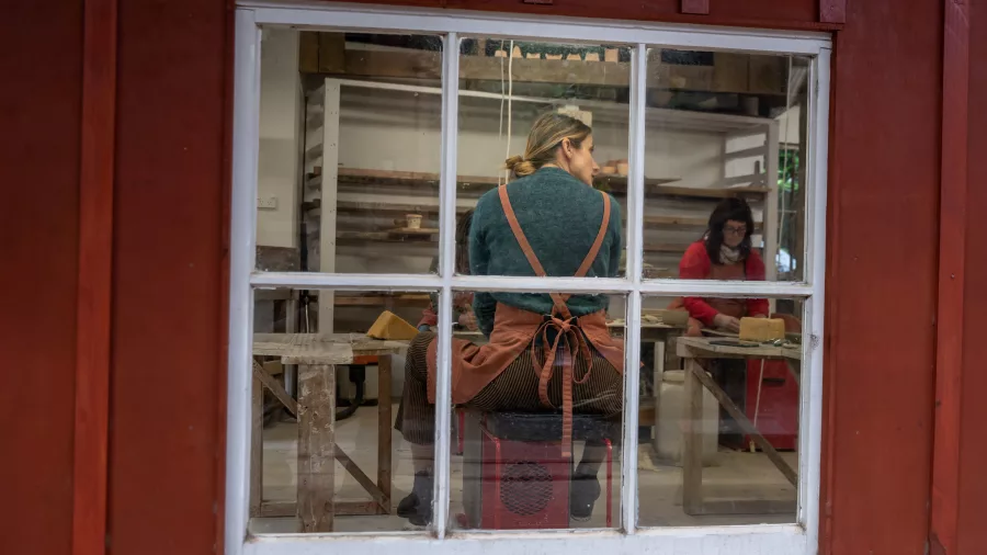 View through window of pottery students in class at Driving Creek