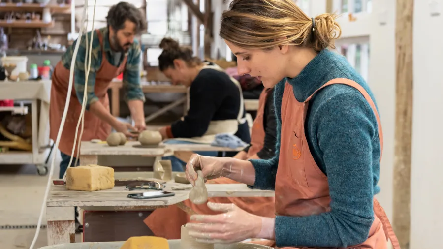 Student shaping clay on a pottery wheel during class at Driving Creek
