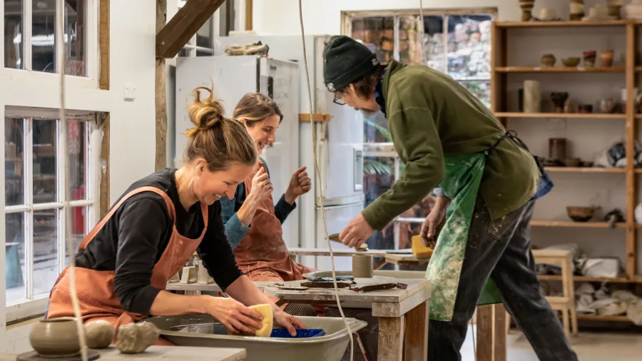 Students cleaning tools and chatting in Driving Creek pottery studio