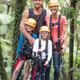 Smiling family in harnesses ready for Coromandel Zipline Tour at Driving Creek