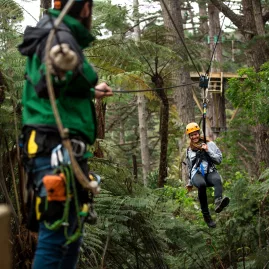 Zipline guide welcomes guest to forest platform at Driving Creek in Coromandel