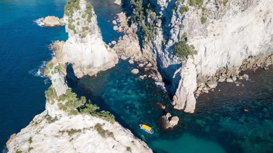 Aerial view of the Glass Bottom Boat navigating volcanic rock formations and sea caves near Cathedral Cove