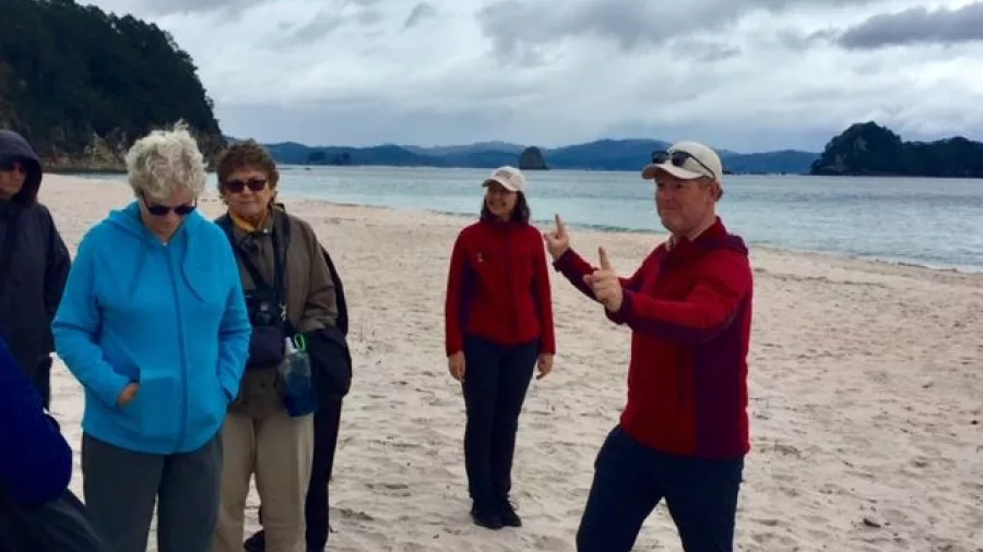 Tour guide with group on Hahei Beach during Coromandel nature tour