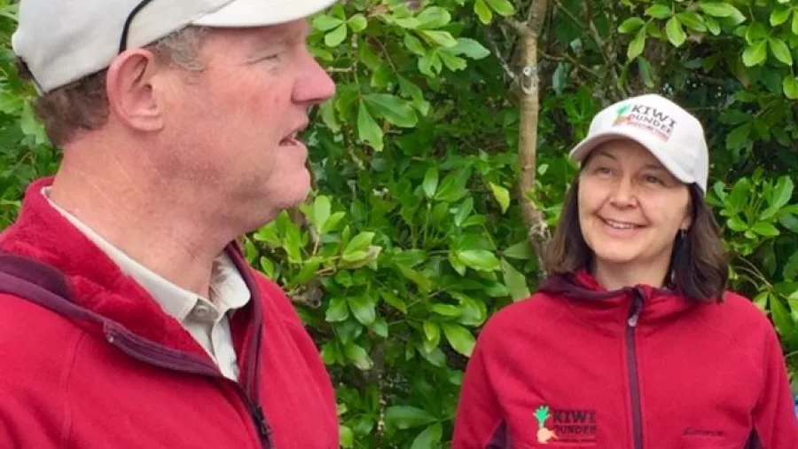 Kiwi Dundee tour guides smiling in branded red jackets and caps in Coromandel