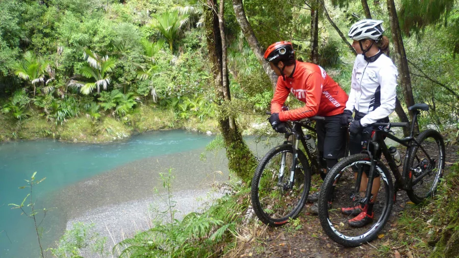 Two cyclists on the Pakihi Track stopping to admire the turquoise river below