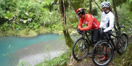 Two cyclists on the Pakihi Track stopping to admire the turquoise river below