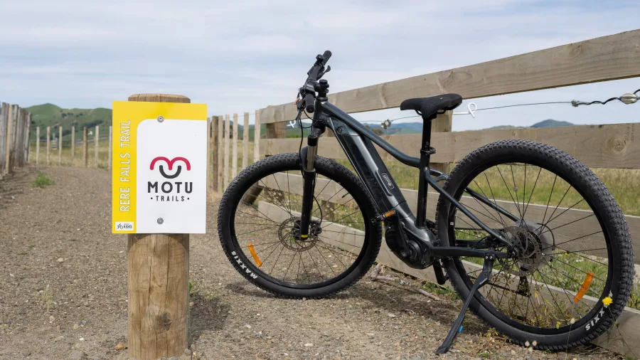 E-bike resting against Motu Trails signpost on the Rere Falls Trail