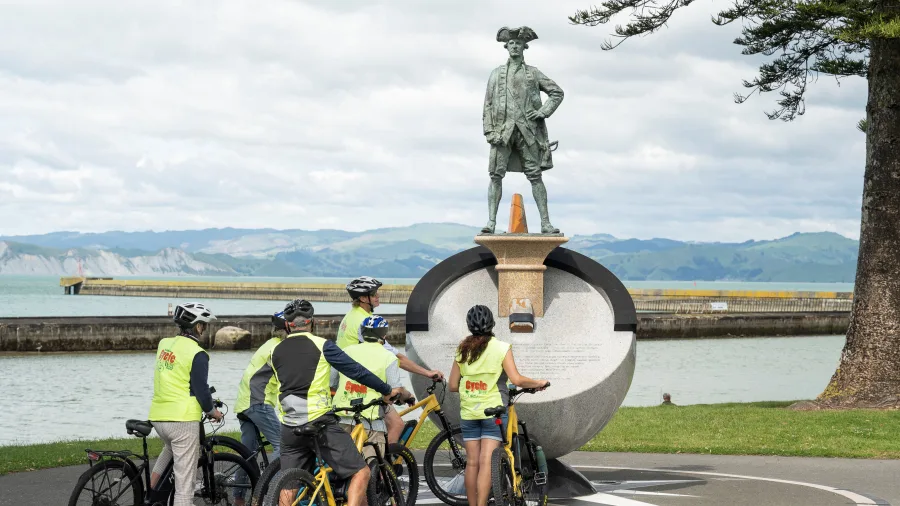 Riders reading the plaque at the Captain Cook Memorial beside the coast