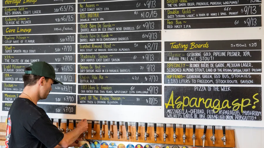 Bartender pouring from taps with Sunshine Brewery beer menu in the background
