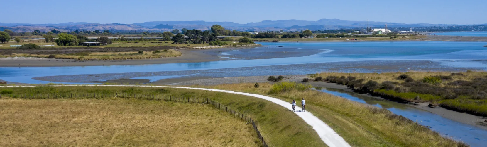 Two cyclists riding along the Clive River Trail with estuary views in Hawke’s Bay