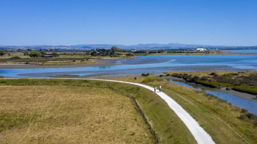 Two cyclists riding along the Clive River Trail with estuary views in Hawke’s Bay