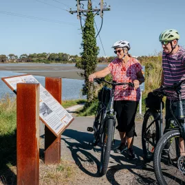 Cyclists reading an information panel beside the estuary on the Hawke’s Bay Cycle Trails