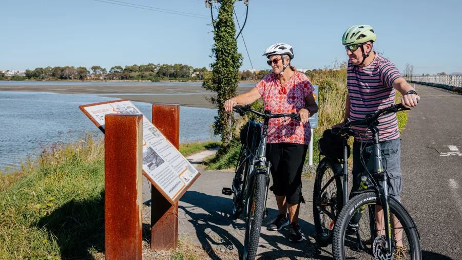 Cyclists reading an information panel beside the estuary on the Hawke’s Bay Cycle Trails