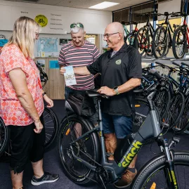 Customers getting cycling advice and maps at Napier City Bike Hire shop with e-bikes on display