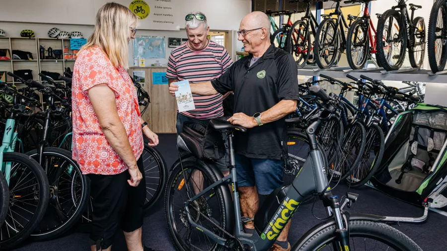 Customers getting cycling advice and maps at Napier City Bike Hire shop with e-bikes on display