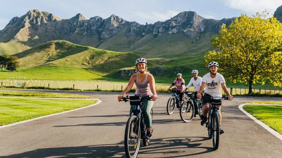 Group of cyclists riding in front of the dramatic Te Mata Peak backdrop at Craggy Range Winery