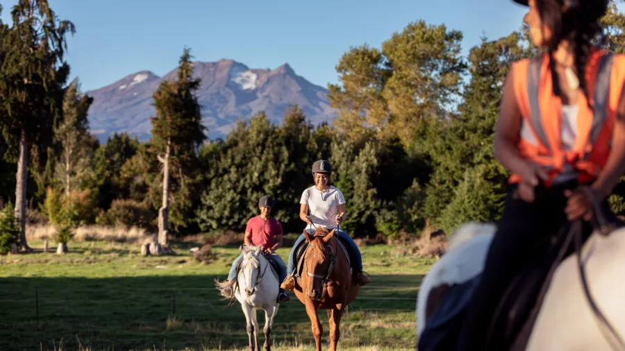 Group horse riding at Ruapehu Homestead with Mount Ruapehu in the background
