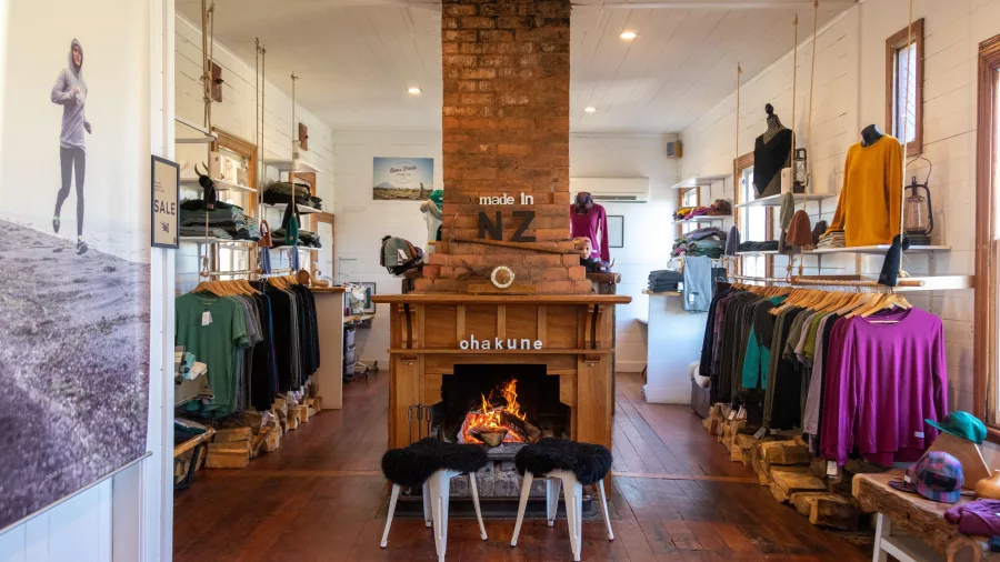 Inside Opus Fresh store in Ohakune showcasing NZ-made clothing around a cosy fireplace