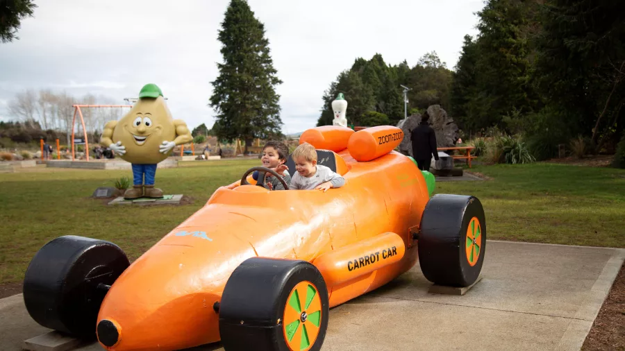 Children playing in the bright orange carrot car at Carrot Park in Ohakune