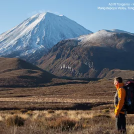 Hiker gazing towards snow-covered Mount Ngauruhoe from the Tongariro Crossing track