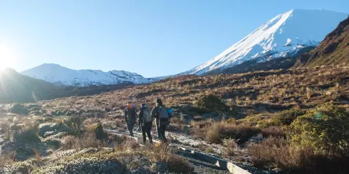 Group walking along a frosty Tongariro trail with Mount Ngauruhoe towering ahead