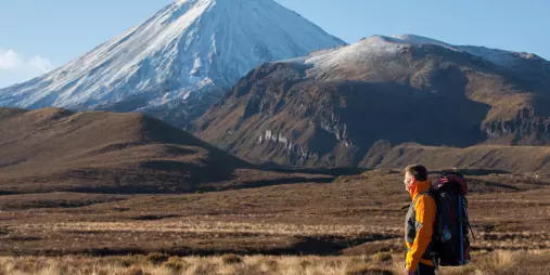 Hiker gazing towards snow-covered Mount Ngauruhoe from the Tongariro Crossing track