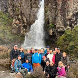 Large tour group posing at the base of Taranaki Falls in Tongariro National Park