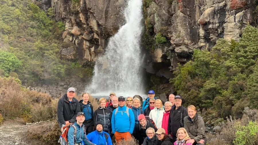 Large tour group posing at the base of Taranaki Falls in Tongariro National Park